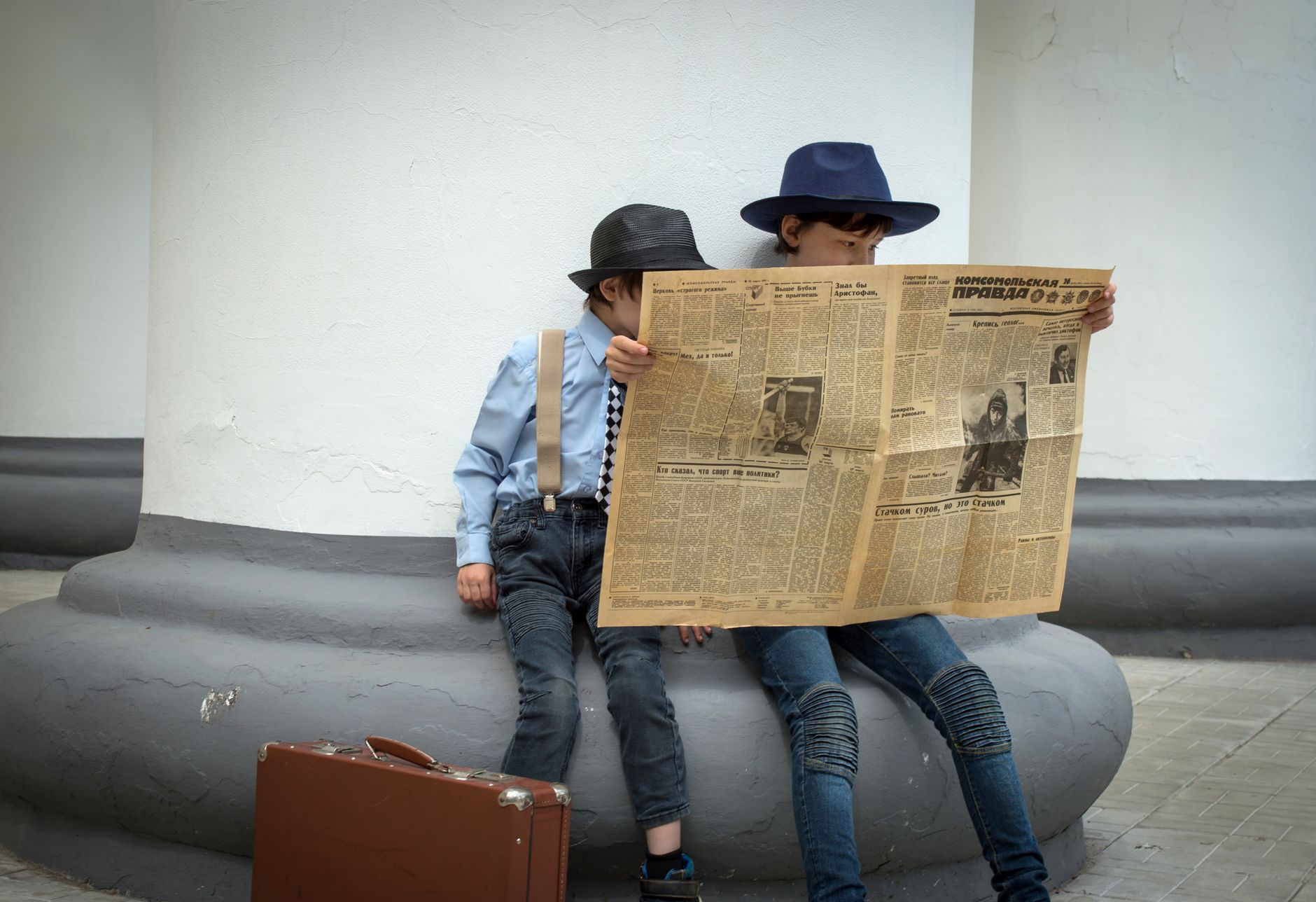 Two stylish children in hats reading a vintage newspaper outdoors. — Strategie wygrywania na klasycznym automacie Book of Ra