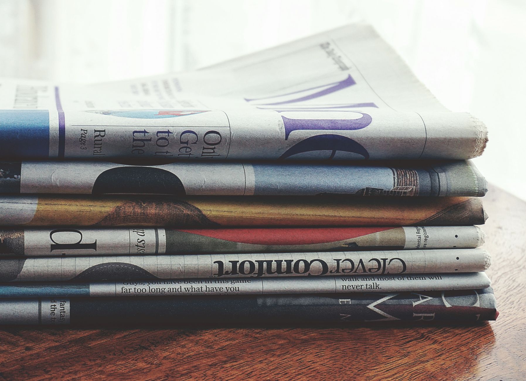 A stack of folded newspapers placed on a wooden table, symbolizing news and information. — Vavada promokoodid ja eelised kasu